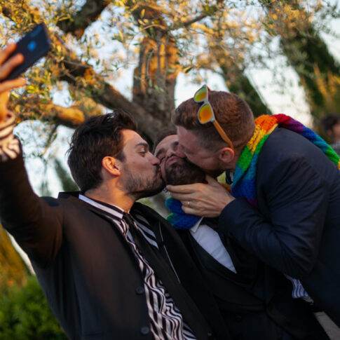 due amici baciano lo sposo mentre si fanno un selfie